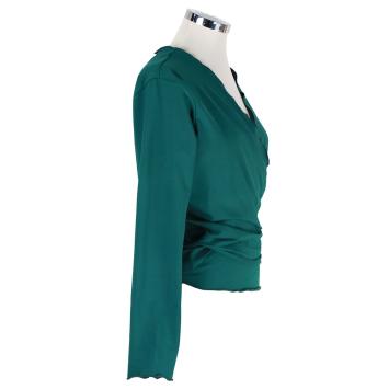 Zijaanzicht van het zachtgroene dames wikkelvest van Atelier CLAU-D. De foto toont de vrouwelijke overslag, de getailleerde p